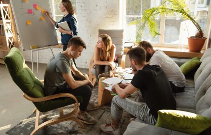 Group of young caucasian office workers meeting to discuss new ideas. Creative meeting. Teamwork and brainstorming. Men and women meet in office to plan their future working. Business concept.