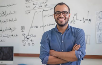 A portrait of an arabic man teacher in front of a whiteboard